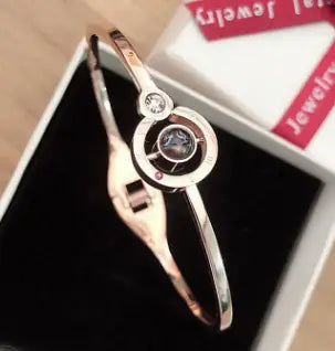 Silver-toned bangle bracelet featuring a circular gemstone detail for elegant jewelry style.