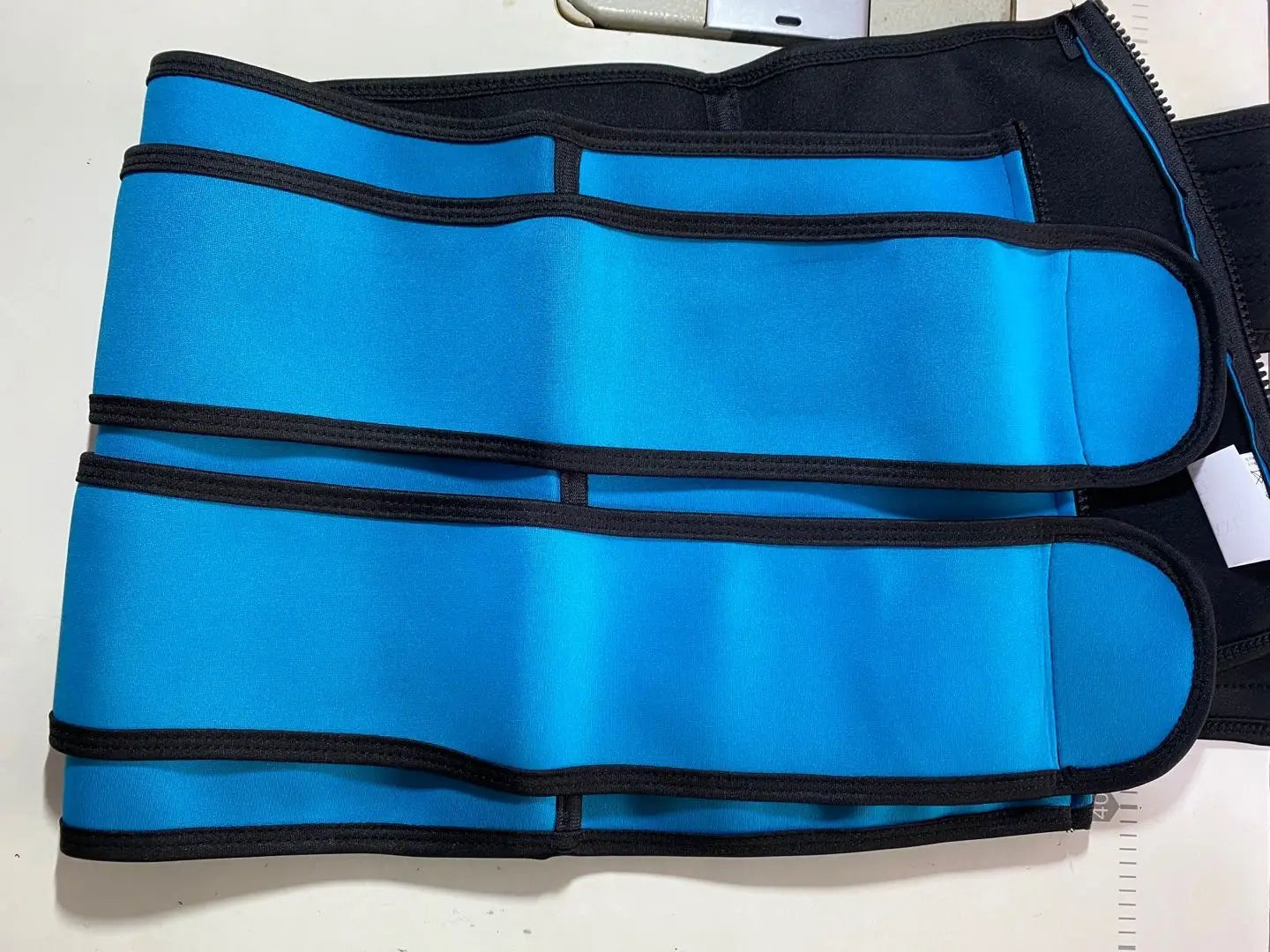 Blue and black waist trainer from The Sports Tuck Belts with adjustable buckle rows.