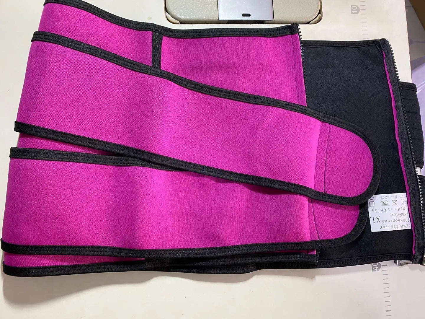 Pink and black waist trimmer in The Sports Tuck Belts with adjustable buckle rows.