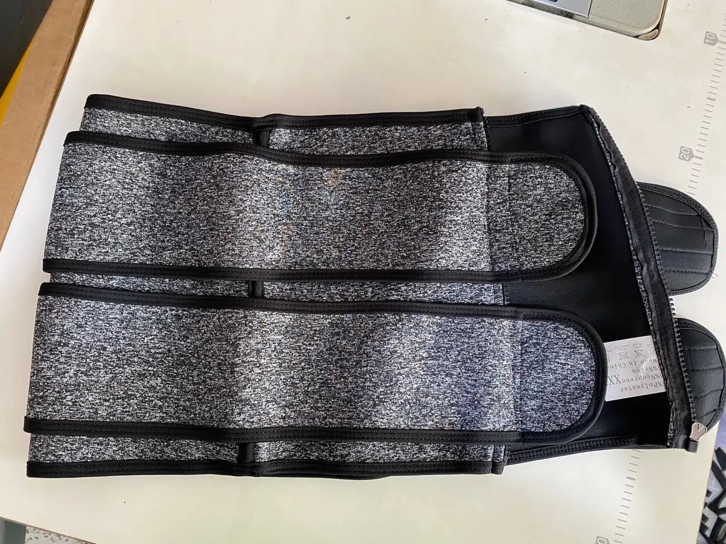 Gray and black waist trainer from The Sports Tuck Belts with adjustable three-row buckle design