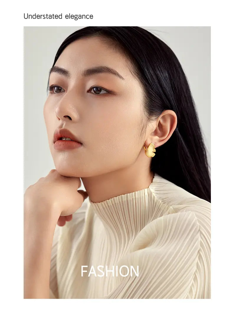 Woman showcasing elegant 14k gold plated 925 Sterling Silver Ginkgo Biloba earrings.