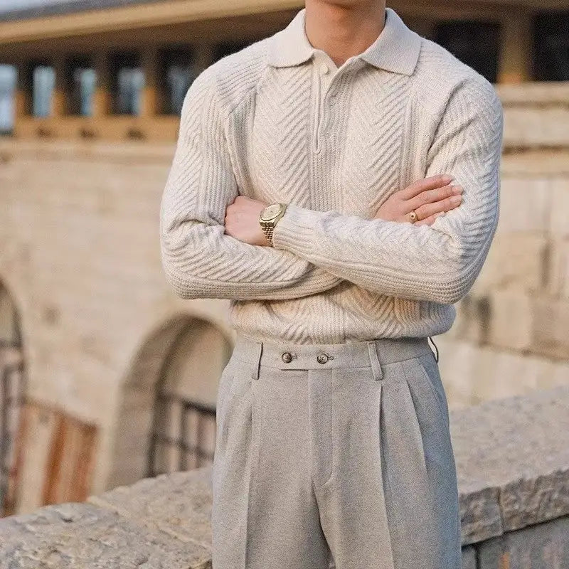 Cream-colored cable knit polo sweater with pleated gray trousers for a stylish winter look.
